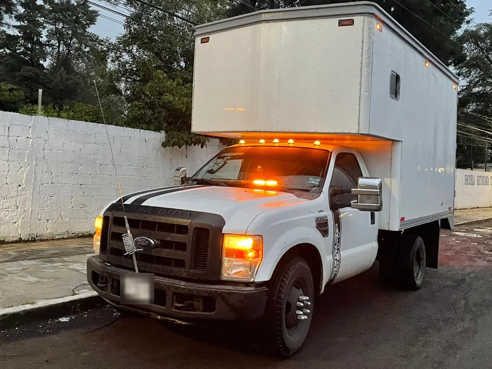 Camión de caja seca de Transportes Contreras con las luces encendidas al anochecer